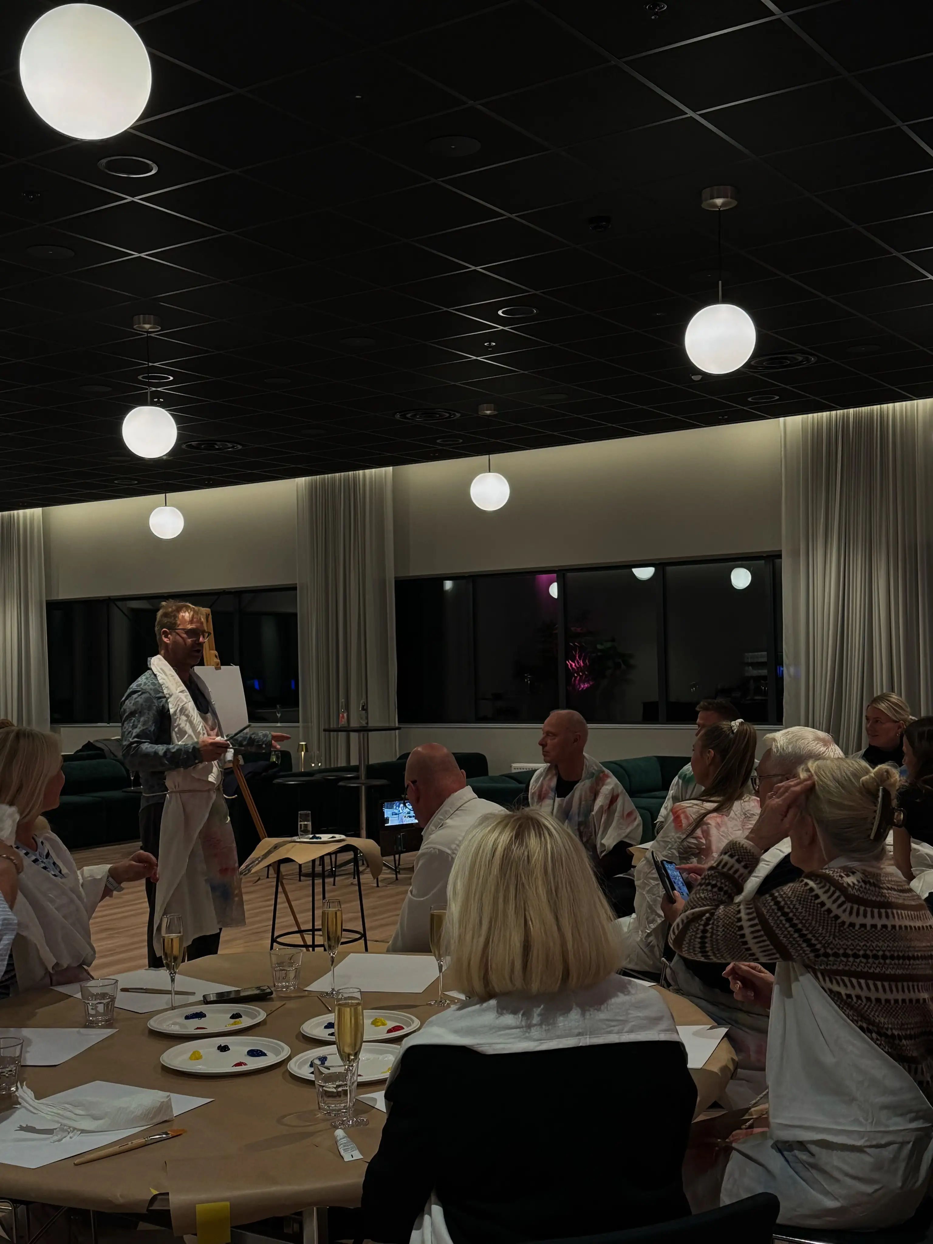 Vebjørn Sand står foran deltakerne under en kreativ malesamling